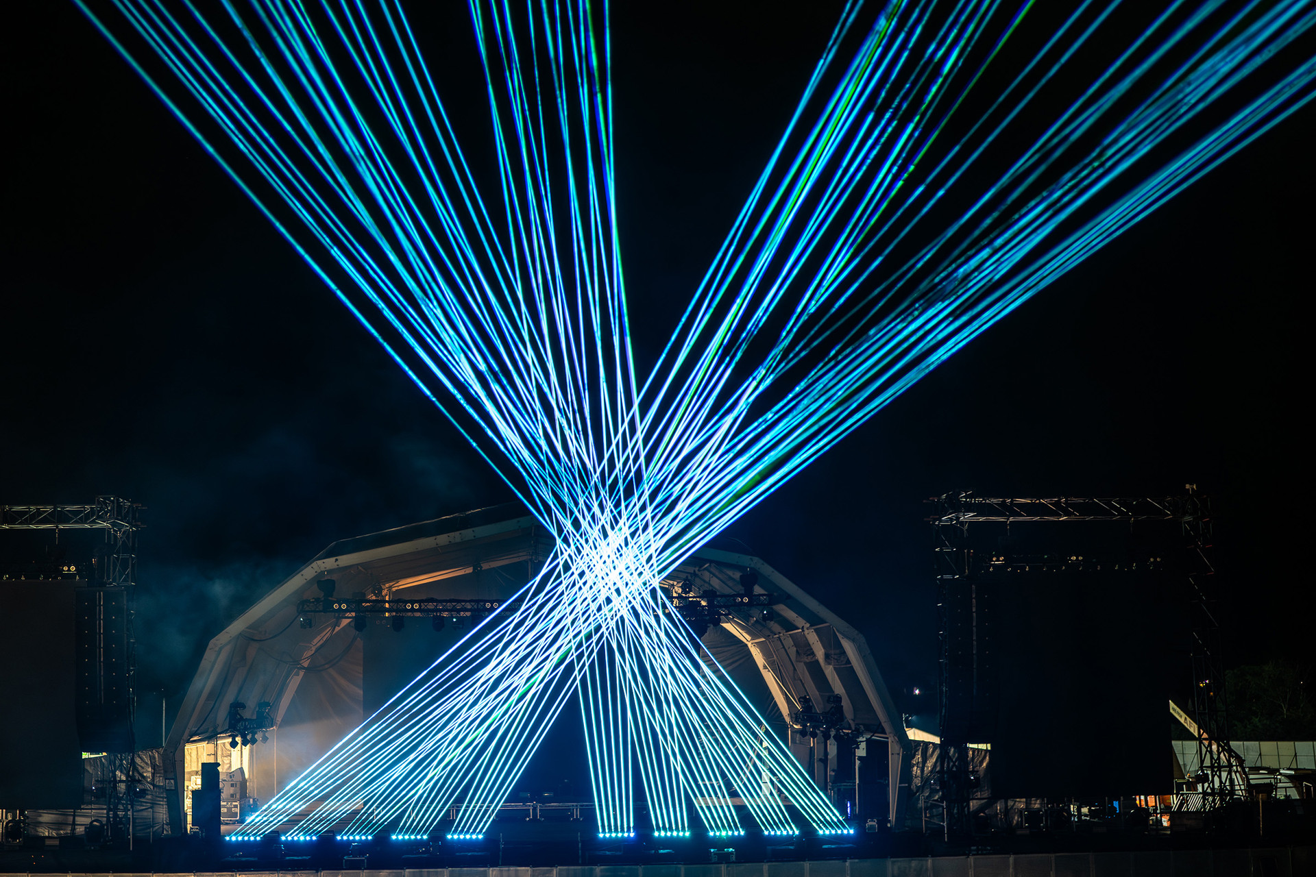 Blaue Laserfächer über einer Bühne
