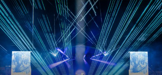 Blaue Laserfächer über einer Bühne